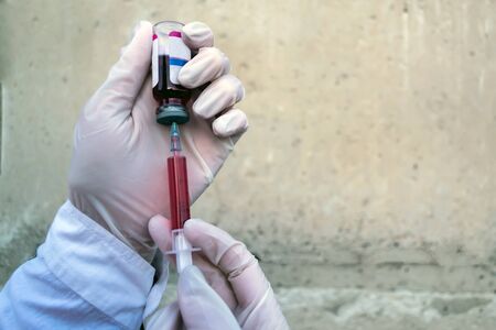 Doctor, researcher or scientist hand in blue glove holding flu, measles, rubella or hpv vaccine and syringe with needle vaccination for baby, child, woman or man shot, medicine vial dose injectionの写真素材