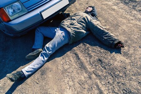 A homeless woman was hit by a car, a woman is lying on the roadの写真素材