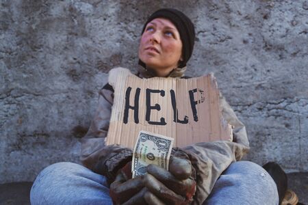 Homeless dirty woman sitting asking passers-by for helpの写真素材