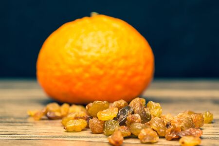 Fresh juicy mandarin and raisins on a wooden background.の写真素材