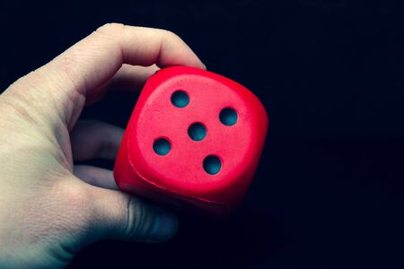 Big dice of red color in a hand on a black backgroundの写真素材