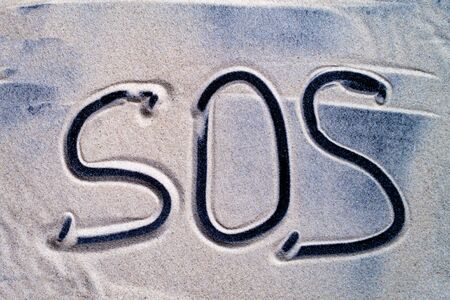 SOS inscription written in sea sand close upの写真素材