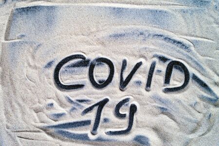 The inscription Covid 19 is written in sea sand close upの写真素材