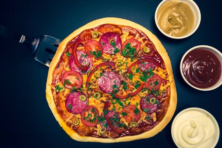 Delicious pizza with cheese and cherry tomatoes on wooden table on dark backgroundの写真素材