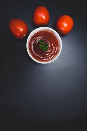 Tomatoes and tomato sauce in a white plate on a black backgroundの写真素材