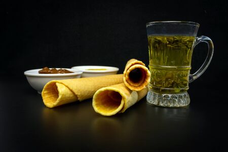Wafer rolls with condensed milk and a saucer, in which there is a filler for waffles, a cup of tea...