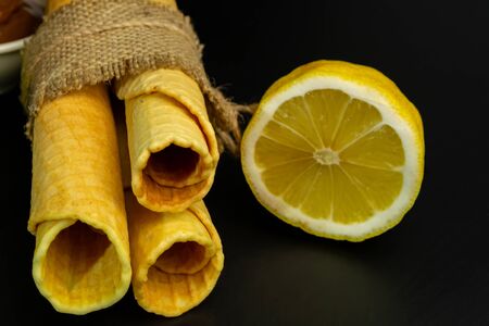 Wafer rolls with condensed milk and lemon on a black backgroundの写真素材