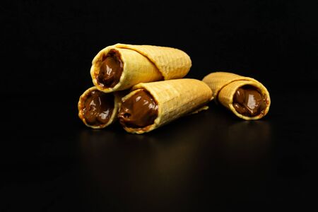 Wafer rolls with condensed milk on a black backgroundの写真素材
