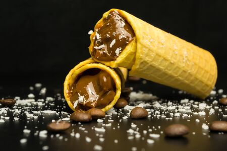 Wafer rolls with condensed milk on a black backgroundの写真素材