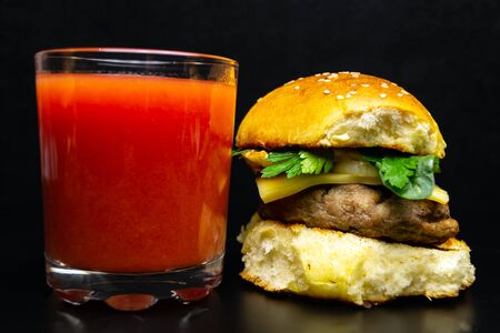 Hamburger and a glass of tomato juice on a black background, junk foodの写真素材