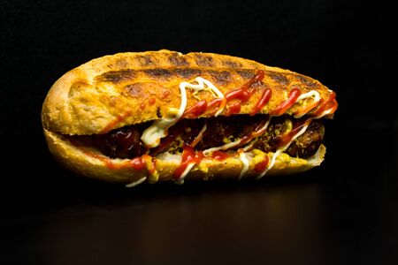 Hot dog on a black background, junk food