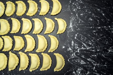 Dumplings on a black background sprinkled with flourの写真素材