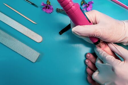 Preparing nails for applying gel polish. Set of cosmetic tools for manicure and pedicure on a black background. Gel polishes, nail files and tongs and a lamp.の写真素材