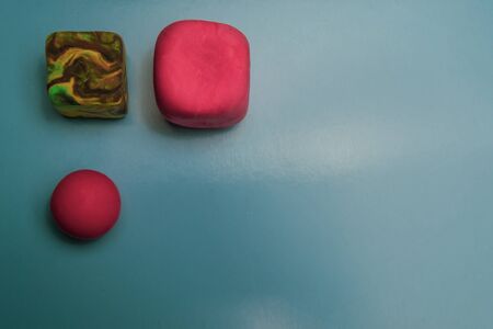 Two cubes and a ball made of plasticine on a blue backgroundの写真素材