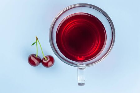 A cup of cherry kampot and two cherries on a blue backgroundの写真素材