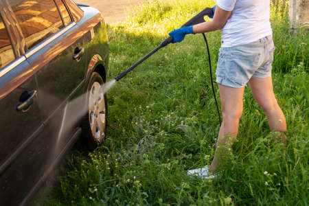 Car wash, a woman in blue gloves washes a car with a Karcherの写真素材
