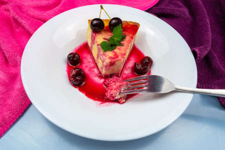 Light breakfast. A fork broke a piece of casserole on a white plate decorated with mint and chopped...
