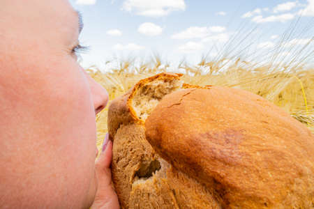 Woman inhales the aroma of freshly baked bread against a blue skyの写真素材