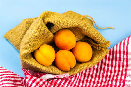 Apricots in a bag on a blue background and a red napkinの写真素材
