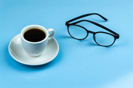 A cup of coffee, black-rimmed glasses. Blue backgroundの写真素材