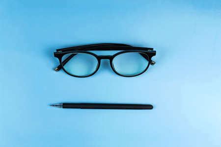Round glasses in black frames lie on a blue backgroundの写真素材