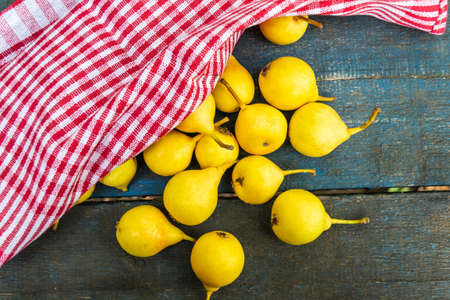 Many yellow sprinkled pears on a blue background covered with a red towel