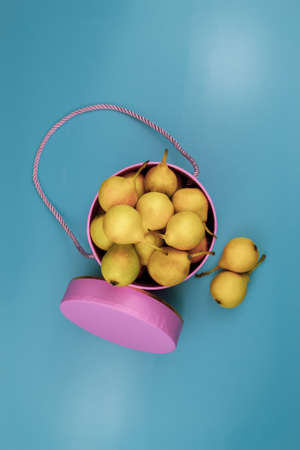 Yellow pears in a pink decorative box. Blue background