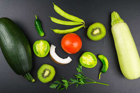 Top view zucchini cucumber kiwi tomato green beans parsley. Black backgroundの写真素材