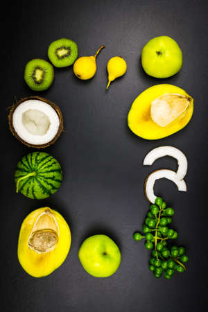 Top view kiwi coconut watermelon mango grapes pear. Black backgroundの写真素材