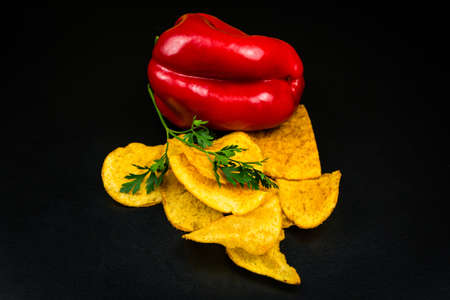 Potato chips and red bell pepper. Black backgroundの写真素材