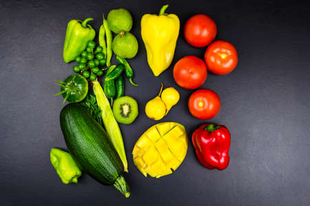 Top view pepper grapes walnut corn kiwi zucchini mango pear tomato. Black backgroundの写真素材