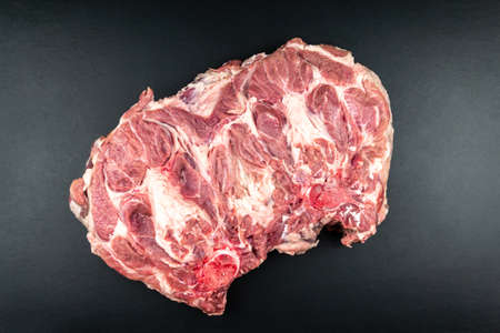 A piece of large fresh raw meat. Black background