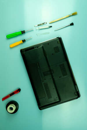 Disassembling a laptop in a repair shop. Laptop, screwdrivers, brushes. Concept for computer...