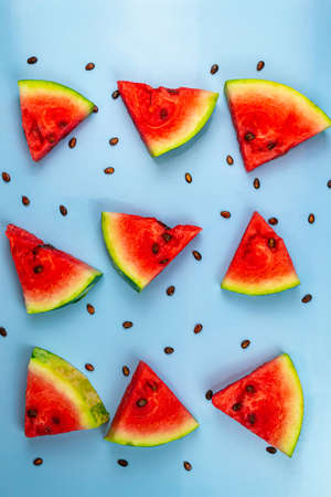 Top view of watermelon slices and watermelon seeds on blue backgroundの写真素材