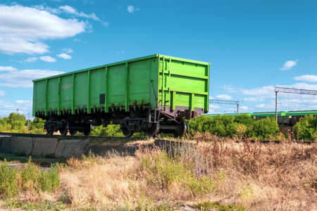Old lonely green freight wagon against the background of the sky