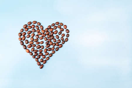 Heart made of coffee beans on a blue background close upの写真素材