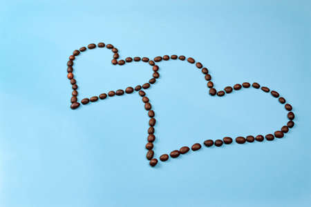 Heart made of coffee beans on a blue background close upの写真素材