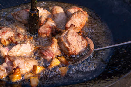 Pieces of bacon and meat are fried in a black pan. Porkの写真素材