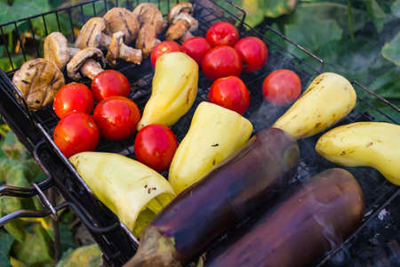 Cooking vegetables over charcoal eggplant, peppers, tomatoes, mushrooms with smokeの写真素材