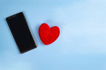 Mobile phone with red heart on blue table backgroundの写真素材