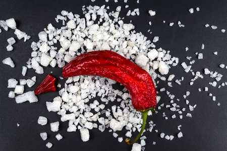 On a black background, cloves of garlic, red chili, traces of coarse sea salt between them.の写真素材