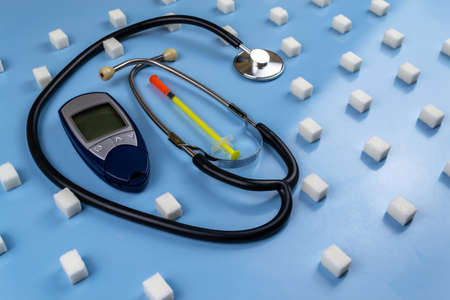 Digital blood glucose meter, stethoscope surrounded by sugar cubes. World Diabetes Dayの写真素材