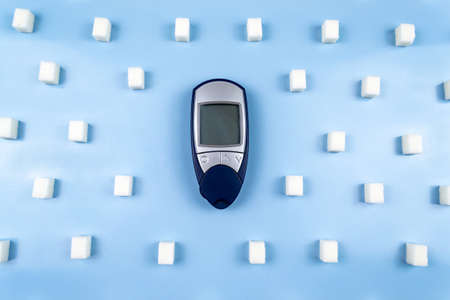 A digital glucometer surrounded by sugar cubes. World Diabetes Dayの写真素材