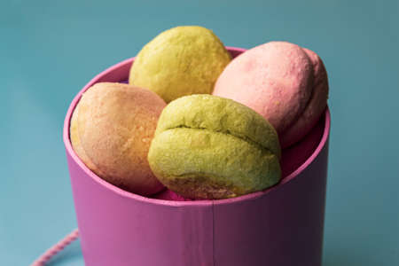 Festive pink box with macaroons on a blue background. Valentine's Day. Close-up, copy space