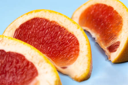 Three slices of grapefruit on a blue table close upの写真素材
