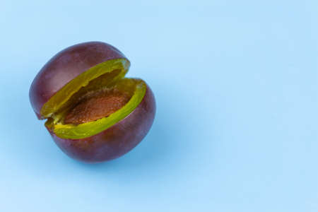 Broken plum on a blue background. Close-up