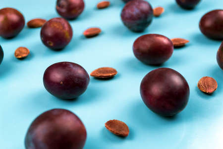 A lot of plums and pits on a blue background. Close-up