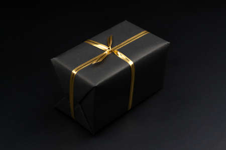 Gift box in black packaging on black background, black friday conceptの写真素材