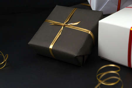 Gift boxes in black and white packaging on black background, black friday concept