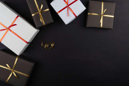 Gift boxes in black and white packaging on black background, black friday concept